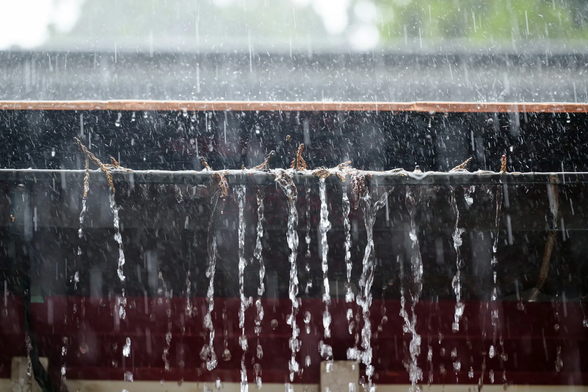 Rain streaming over the lip of an overflowing gutter, showing why gutter sizing and downspout placement matter for heavy rain in Duluth