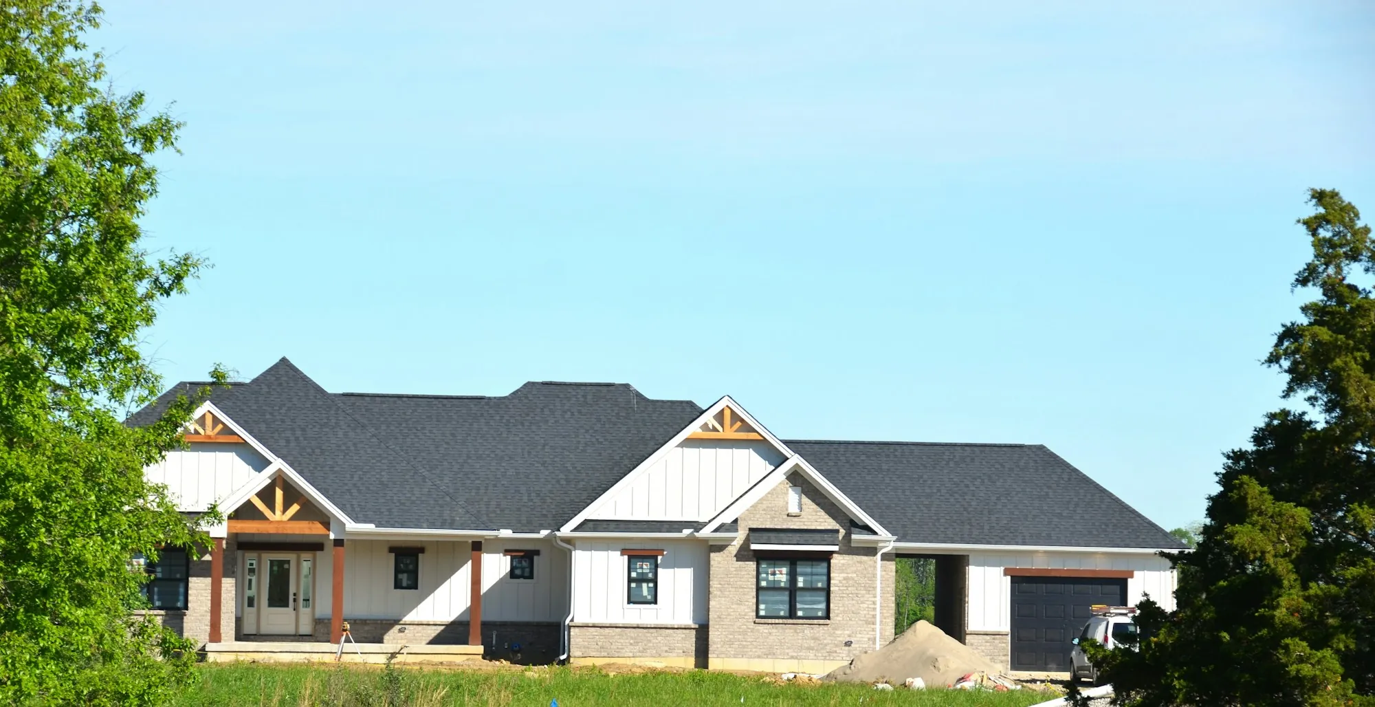 White farmhouse-style home with a charcoal shingle roof and wood trim